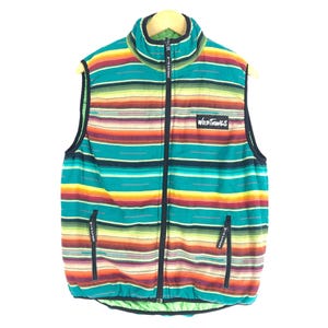 May include: A sleeveless vest with a colorful striped pattern in shades of green, orange, red, yellow, and black. The vest has a zipper closure and a black label with the text "WILD THINGS" on the front.