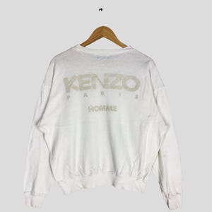 Może przedstawiać: Biała bluza z długim rękawem z kremowym logo KENZO PARIS HOMME z tyłu.