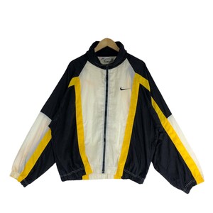 May include: A black, white, and yellow windbreaker jacket with a zipper closure and a Nike logo on the chest.