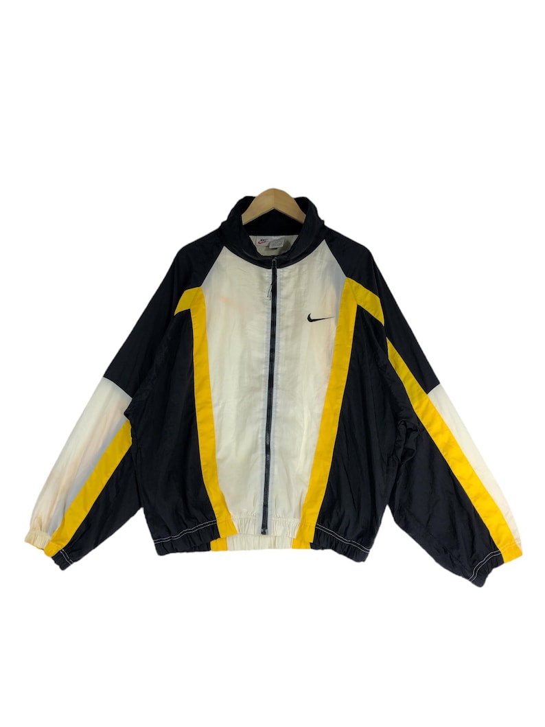 May include: A black, white, and yellow windbreaker jacket with a zipper closure and a Nike logo on the chest.