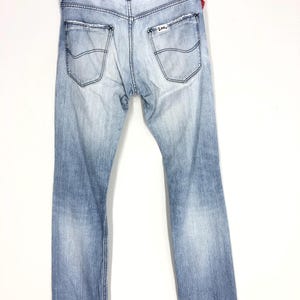 May include: Light blue denim jeans with a faded look and frayed hems. The jeans have a small Levi's patch on the back right pocket.