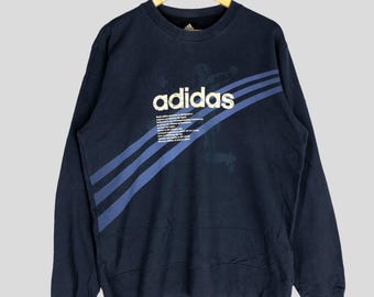 May include: A navy blue sweatshirt with a white adidas logo and three blue stripes on the front. The sweatshirt has a crew neck and long sleeves.