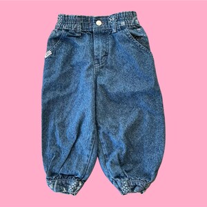 May include: A pair of blue denim jeans with a gathered elastic waistband and a cuffed hem.