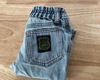May include: Light blue denim jeans with a small green and brown patch that says "Classic Style" on the back pocket.
