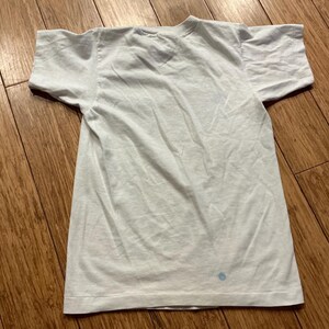 May include: A plain white t-shirt with a crew neck and short sleeves. The shirt is made of a soft, lightweight fabric.