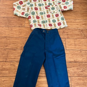 May include: A white short-sleeved button-down shirt with a repeating pattern of red, green, and yellow traffic lights with the text "Be Careful" on each light. The shirt is paired with dark blue pants.