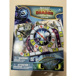 May include: A board game titled "How to Train Your Dragon: The Hidden World Path Game." The box features a colorful design with images of dragons and a circular game board. The game is for ages 3+ and includes a warning about small parts.