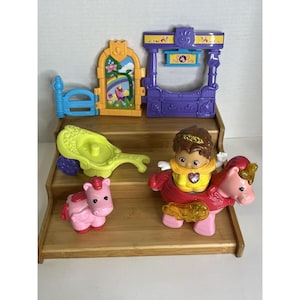 May include: A plastic toy set featuring a purple archway, a yellow window frame with a rainbow unicorn graphic, a lime green carriage, a small pink pony figure, and a larger pink pony figure with a brown-haired character figurine riding it.