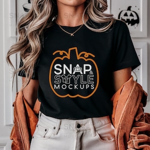 以下が含まれることがあります： 「SNAP & STYLE MOCKUPS」というテキストが入ったカボチャの白いグラフィックが描かれた黒いTシャツです。