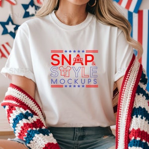 Op de afbeelding: Wit T-shirt met rode en blauwe tekst die "SNAP & STYLE MOCKUPS" zegt met sterren en een camera-icoon.