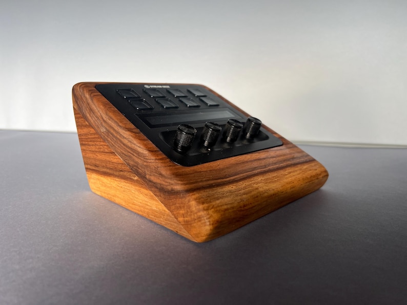 以下が含まれることがあります： ボタンとノブを備えた黒いコントロールパネルを備えた木製の電子デバイス。デバイスは、豊かで温かみのある木目仕上げと洗練されたモダンなデザインです。コントロールは黒です。