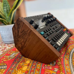 May include: A dark wood stand for a black and blue synthesizer with the word "Digitone" printed on the front.