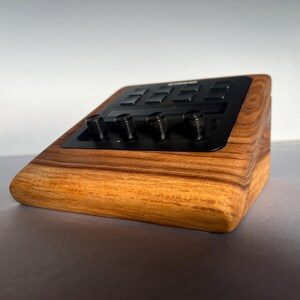 以下が含まれることがあります： 黒いコントロールパネルとノブを備えた木製の電子機器。デバイスは、丸みを帯びたエッジと天然の木目仕上げの長方形の形状をしています。コントロールパネルには、いくつかのボタンとノブがあります。