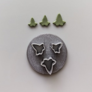 Peut inclure: Un ensemble de trois emporte-pièces en forme de papillons. Les emporte-pièces sont en métal argenté et sont disposés sur un fond gris. Trois emporte-pièces en forme de feuilles vertes sont également visibles sur l'image.