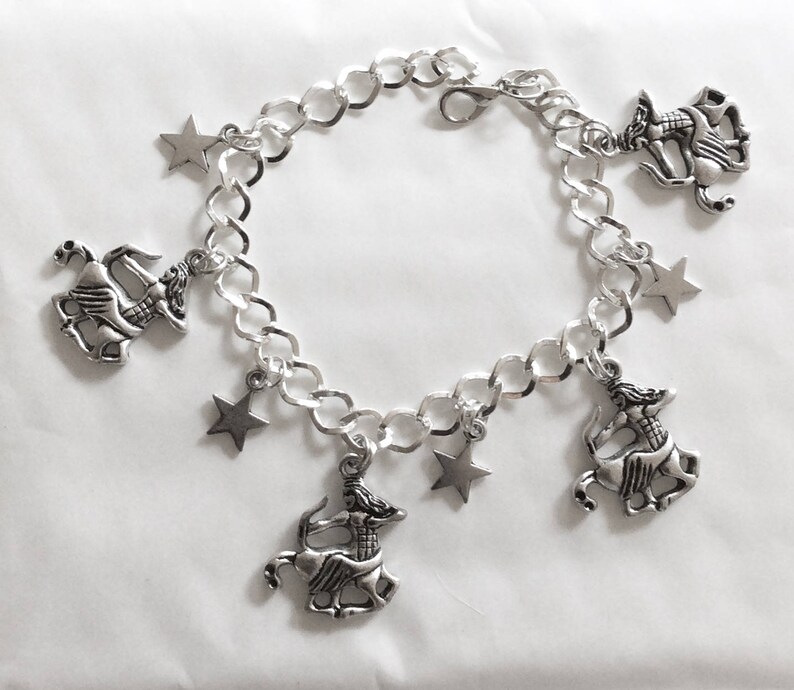 Op de afbeelding: Een zilveren armband met vijf bedels: vier stervormige bedels en een bedel die een centaur met pijl en boog voorstelt. De armband is gemaakt van een zilveren ketting.