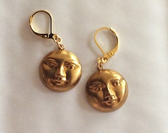 Könnte beinhalten: Ein Paar goldene Ohrringe mit einem Mondgesichtsdesign. Die Ohrringe sind aus Metall und haben einen Hakenverschluss.