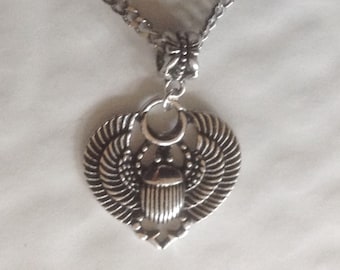 May include: Silver necklace with a heart-shaped pendant featuring a scarab beetle design with wings and a crescent moon.