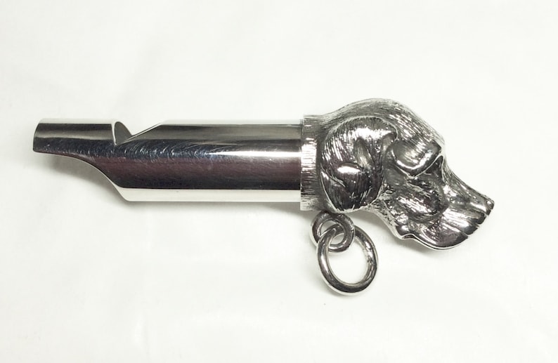 May include: Silver dog whistle with a detailed dog head design. The whistle has a ring attached for easy carrying.