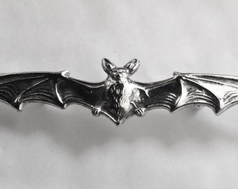 May include: Silver-toned metal bat brooch with detailed wings and a textured body.