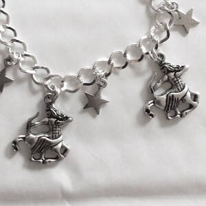 Op de afbeelding: Een zilveren armband met een zilveren ketting en meerdere bedels. De bedels zijn een ster en een centaurfiguur.