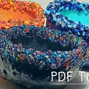 May include: Three decorative bowls with beaded edges. The bowls are orange, blue, and black. The beads are various colors, including orange, blue, and purple. The bowls are arranged in a pyramid shape. The text "PDF Tutorial" is visible at the bottom of the image.