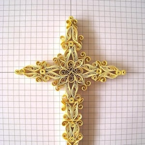 May include: A yellow paper quilling cross with intricate designs. The cross is made of many small, rolled paper pieces that are glued together to create a delicate and intricate design.