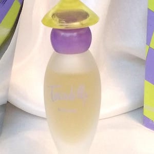 May include: A perfume bottle with a yellow conical cap and a purple spherical base. The bottle is a pale yellow colour with the word "Twinkly" in a cursive font. The bottle is on a white background.