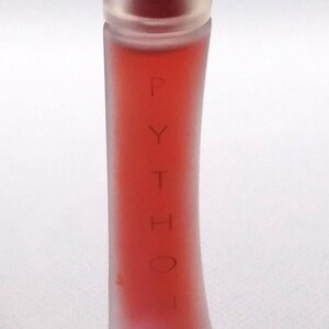 Peut inclure: Un flacon de parfum cylindrique, haut et fin, en verre dépoli. Le flacon contient un liquide rouge vif. Le mot PYTHON est imprimé verticalement en lettres fines et sombres sur le devant, avec le nom TRUSSARDI inscrit en dessous.