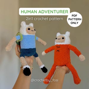 Pode incluir: Duas bonecas de crochê feitas à mão, uma azul e outra laranja, que se assemelham a personagens de desenhos animados. As bonecas têm chapéus brancos, rostos sorridentes e são seguradas por mãos. O texto na imagem diz "HUMAN ADVENTURER" e "2in1 crochet pattern".