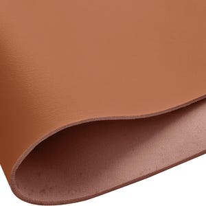 May include: Close-up of a sheet of brown leather. The leather is smooth and has a slight sheen. The edges are curved, revealing a lighter brown underside. The overall appearance suggests a high-quality material suitable for various crafting projects.