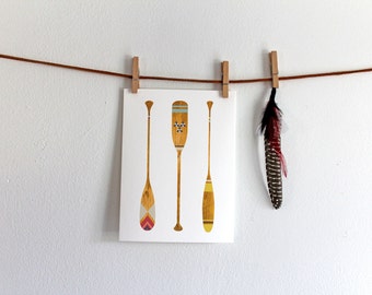 May include: Three wooden paddles with geometric patterns and a single brown feather hanging from a string with wooden clothespins.