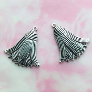 May include: Two silver metal pendant charms in the shape of a stylized flower with a pointed top and multiple layers of petals.