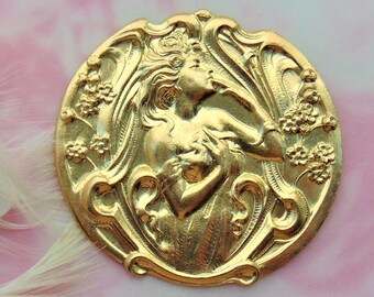 May include: A gold-toned metal pendant featuring a raised design of a woman's face with flowing hair and floral accents.