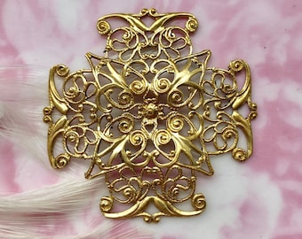 May include: A gold filigree cross pendant with intricate details. The cross is made of metal and has a delicate, ornate design.
