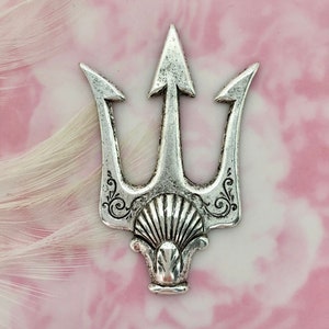 May include: Silver-toned metal trident charm with a decorative shell design at the base. The trident has three prongs and a pointed tip.