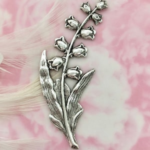 May include: Silver charm featuring a stylized lily of the valley flower with delicate leaves. The charm is a single piece with a detailed design.