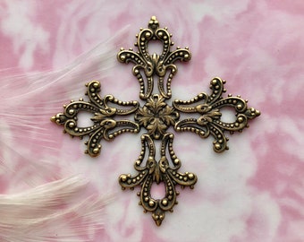May include: A gold-toned metal cross with a decorative, ornate design. The cross has a floral pattern and is detailed with small beads.