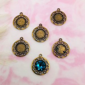 May include: Five antique gold-toned metal pendant charms with a decorative filigree design. One charm features a blue gemstone in the center.