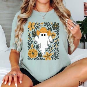 Bay Comfort Colors t-shirt featuring a cute ghost wearing a cowboy hat, surrounded by yellow and green floral designs—perfect for fall, Halloween, and western style lovers.