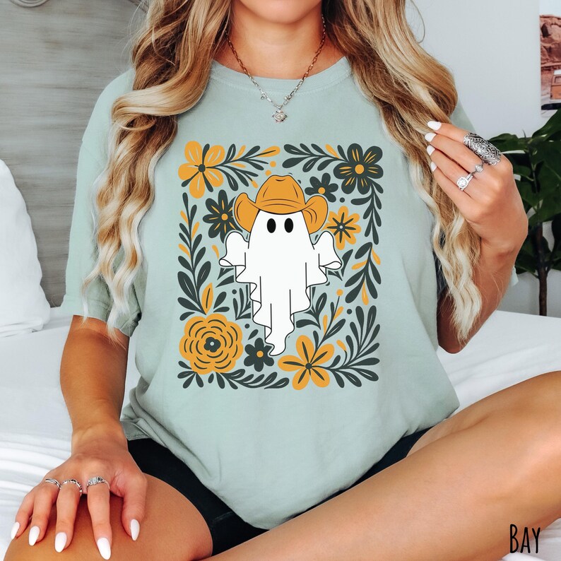 Bay Comfort Colors t-shirt featuring a cute ghost wearing a cowboy hat, surrounded by yellow and green floral designs—perfect for fall, Halloween, and western style lovers.