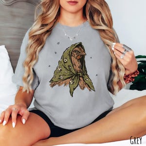 Grey Comfort Colors unisex t-shirt featuring an illustrated hen wearing a green floral headscarf.