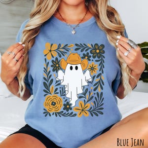 Blue jean Comfort Colors t-shirt featuring a cute ghost wearing a cowboy hat, surrounded by yellow and green floral designs—perfect for fall, Halloween, and western style lovers.
