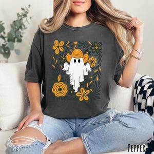 Pepper Comfort Colors t-shirt featuring a cute ghost wearing a cowboy hat, surrounded by yellow and green floral designs—perfect for fall, Halloween, and western style lovers.