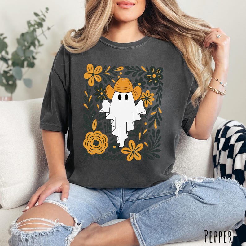 Pepper Comfort Colors t-shirt featuring a cute ghost wearing a cowboy hat, surrounded by yellow and green floral designs—perfect for fall, Halloween, and western style lovers.