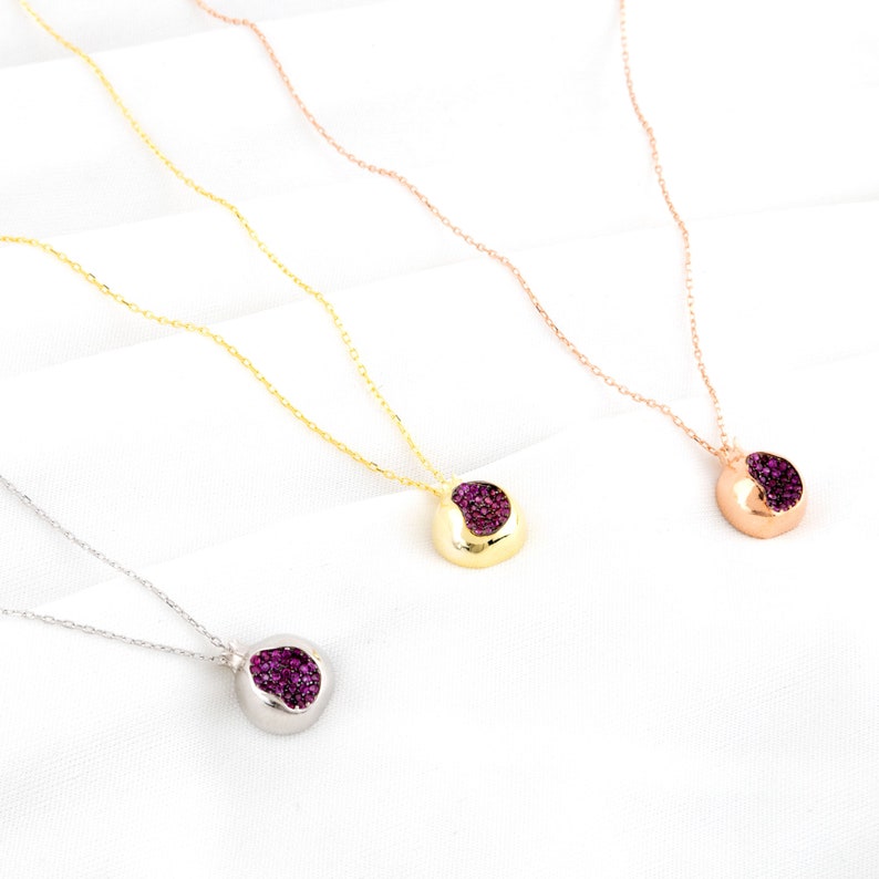 May include: Three silver necklaces with a small, round pendant featuring a purple stone. The necklaces are on a white background.