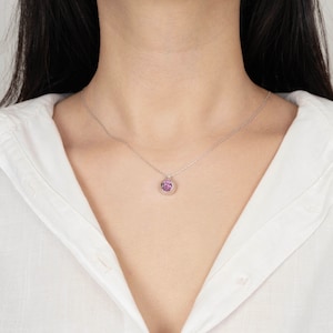 May include: A silver chain necklace with a small pendant featuring a pink gemstone.