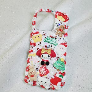 K&ouml;nnte beinhalten: Ein wei&szlig;es Handy-Case mit Weihnachtsmotiv. Das Case ist mit roten und wei&szlig;en Zuckerstangen, einem Lebkuchenmann, einem Schneemann, einem Weihnachtsbaum, einem Weihnachtsmann, einer Schneeflocke, einem Herz, einer Wolke und einem Charakter aus der Hello Kitty-Reihe verziert. Das Case tr&auml;gt au&szlig;erdem die Aufschrift "Merry Christmas".