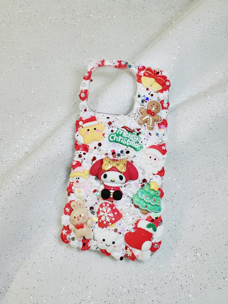 K&ouml;nnte beinhalten: Ein wei&szlig;es Handy-Case mit Weihnachtsmotiv. Das Case ist mit roten und wei&szlig;en Zuckerstangen, einem Lebkuchenmann, einem Schneemann, einem Weihnachtsbaum, einem Weihnachtsmann, einer Schneeflocke, einem Herz, einer Wolke und einem Charakter aus der Hello Kitty-Reihe verziert. Das Case tr&auml;gt au&szlig;erdem die Aufschrift "Merry Christmas".