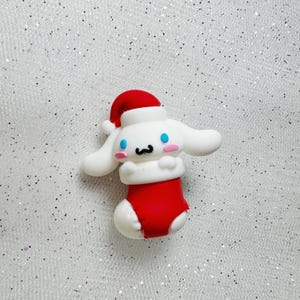 K&ouml;nnte beinhalten: Wei&szlig;er und roter Weihnachtssocken mit einem niedlichen Cartoon-Hund, der einen Weihnachtsmann-Hut tr&auml;gt. Der Hund hat blaue Augen und eine rosa Nase.