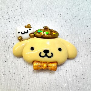Peut inclure: Un chien jaune avec un n&oelig;ud papillon marron et un chapeau vert et or. Le chien porte un chat blanc sur la t&ecirc;te. Le chien est fait en p&acirc;te polym&egrave;re.